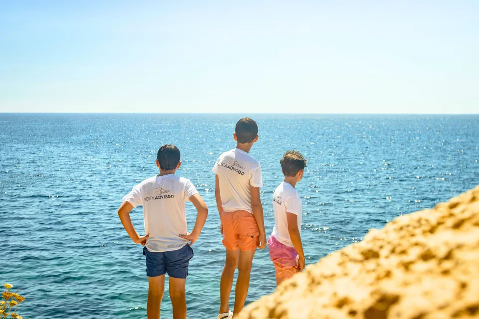 Three Easter Camp children looking out over the sea from the rocks in Jávea