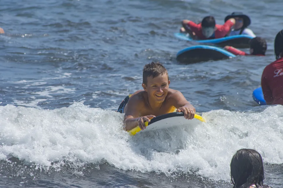 A Surf Camp child riding a wave on a bodyboard at the Arenal beach in Jávea